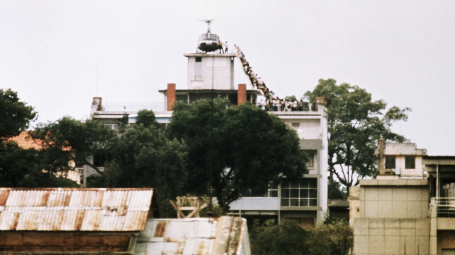 April 29, 1975 – A member of the CIA helps evacuees up a ladder onto an Air America helicopter shortly before Saigon fell to advancing North Vietnamese troops. (Photo from Wikimedia Commons)