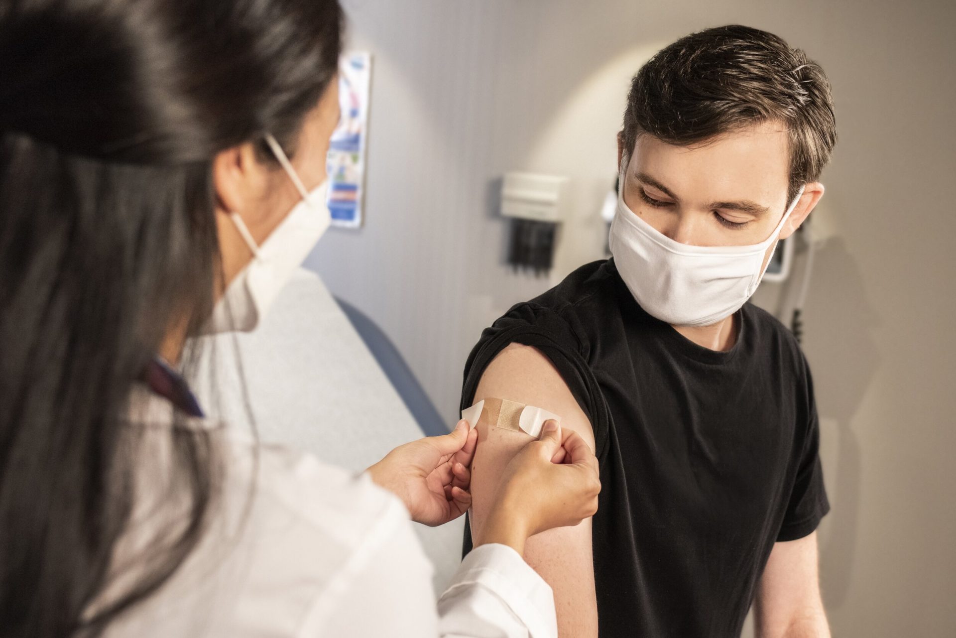 In this 2020 photograph, captured inside a clinical setting, a health care provider places a bandage on the injection site of a patient, who just received an influenza vaccine. (Photo by the CDC | Unsplash)