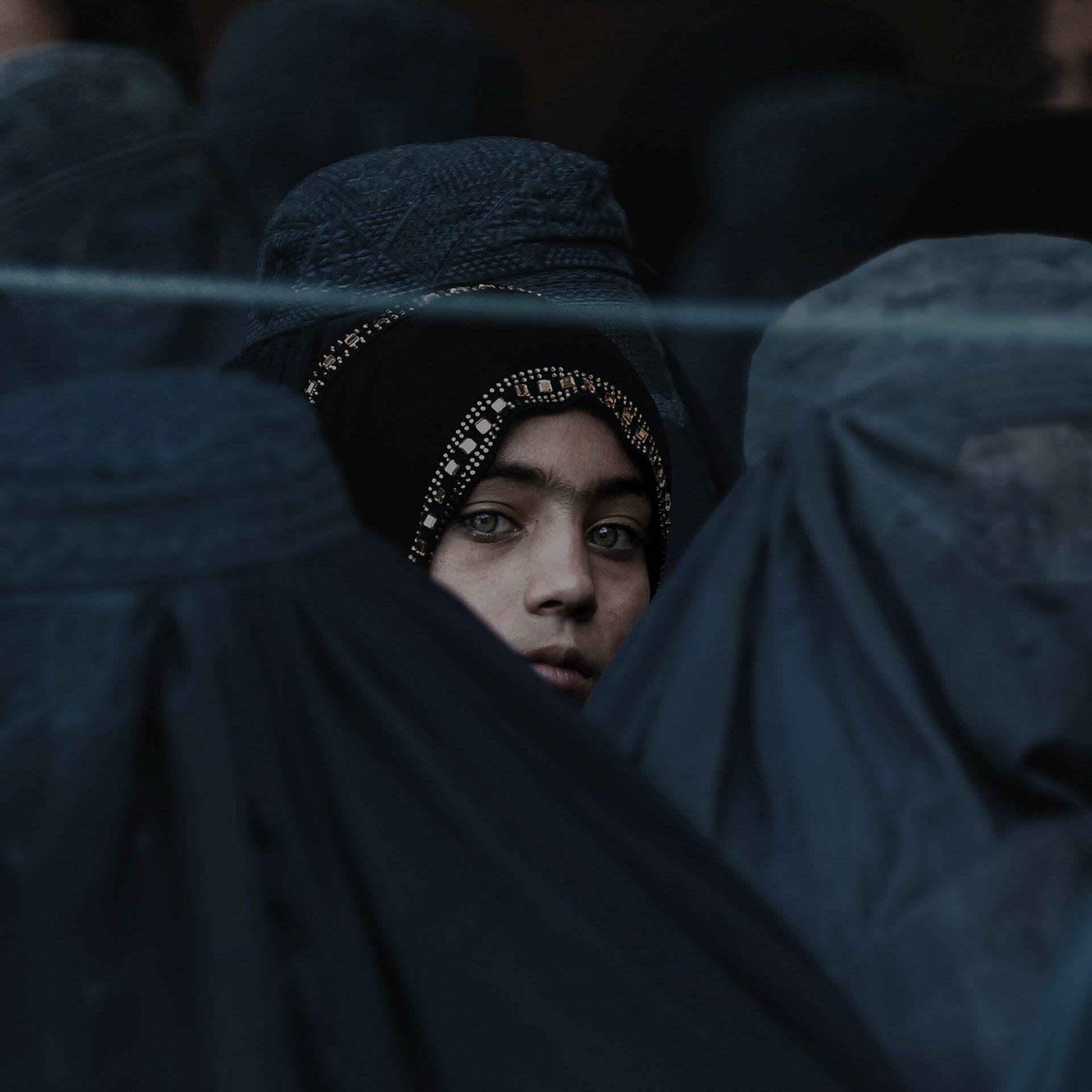 Jalalabad, Afghanistan – A girl looks on among Afghan women lining up to receive relief assistance during the holy month of Ramadan. (Photo by Isaak Alexandre Karslian | Unsplash)