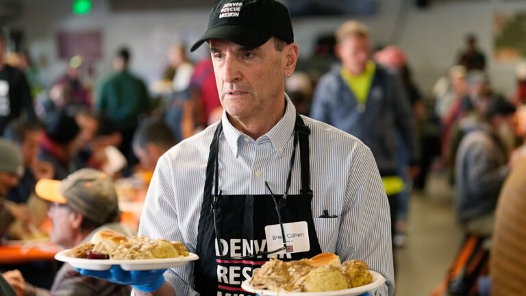 Volunteer Brent Cohen carries plates of food to guests during the annual Thanksgiving banquet at the Denver Rescue Mission on Nov. 22, 2023, in Denver. (AP Photo/David Zalubowski, File)